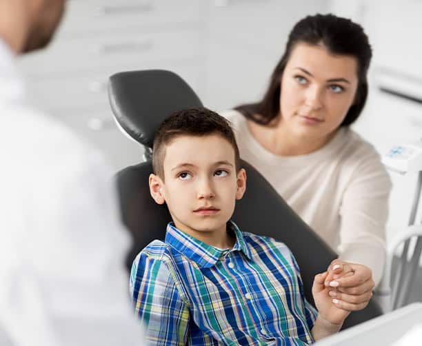 Child And Mother Consulting Dentist During Pediatric Visit