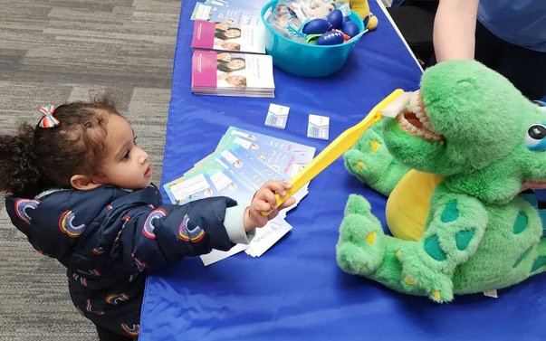 Child Learning To Brush Teeth With Toy Dinosaur