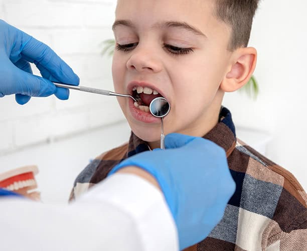 Dentist Examining Child Teeth With Dental Mirror