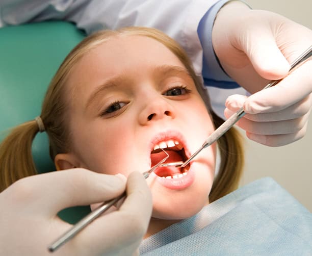 Dentist Examining Girls Teeth During Dental Checkup