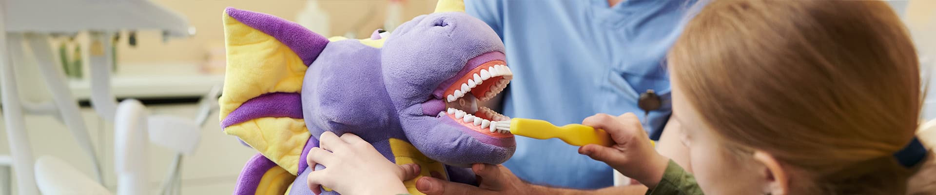 Pediatric Dentist Teaching Child Brushing With Dragon Toy